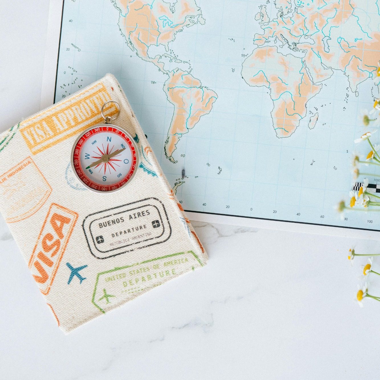 Pasaporte con sellos y una brújula sobre un mapa mundi.